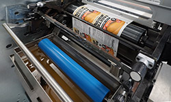 Obraz przedstawia
              proces druku UV na maszynie drukarskiej